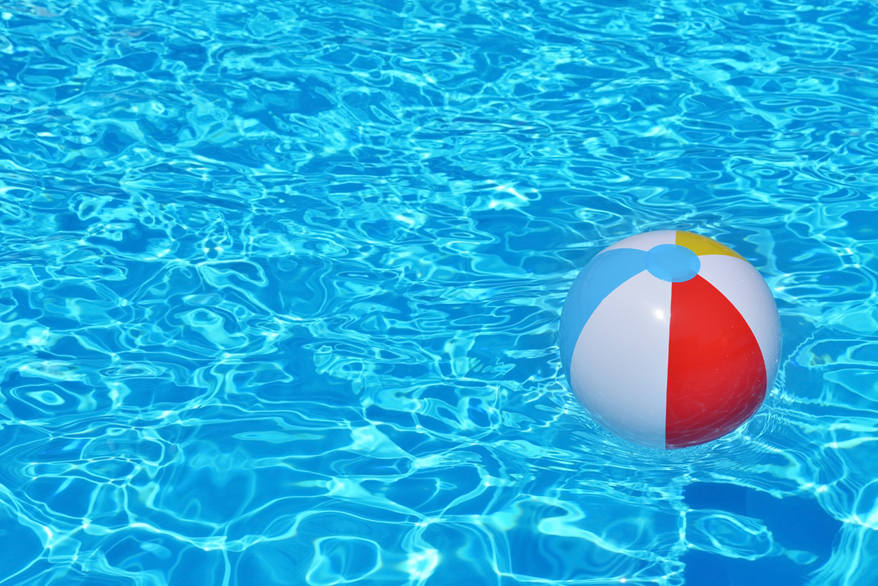 Colorful inflatable ball floating in swimming pool, summer vacation concept